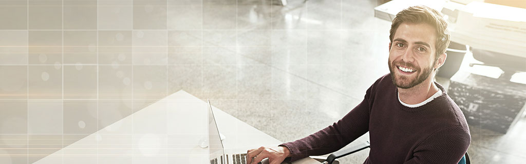 A képen egy mosolygó laptopon dolgozó féfi látható